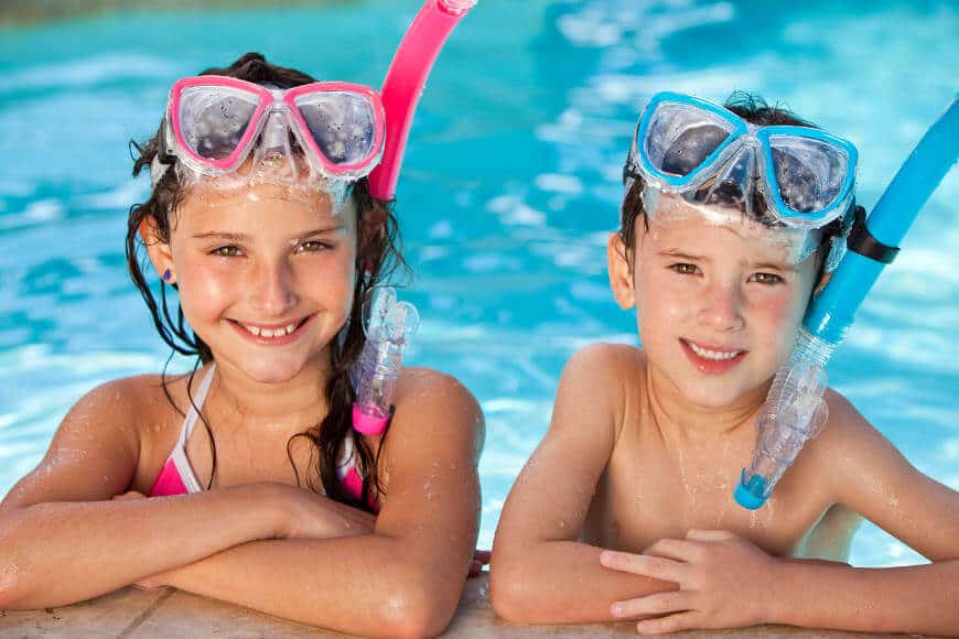Two kids in a swimming pool with googles and snorkels