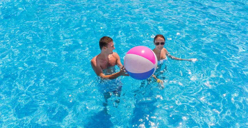 Young couple in a swimming pool with a beach ball